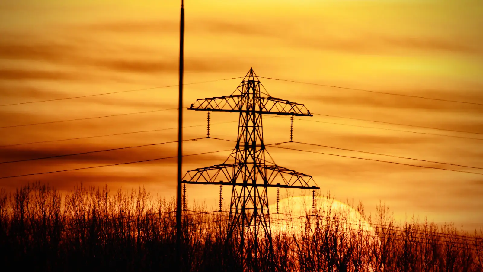 Power transmission tower under red sunset.