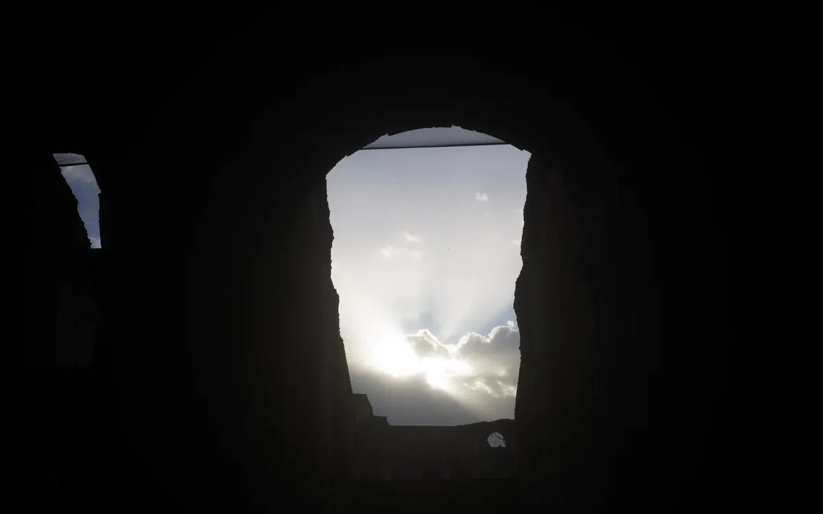 Dark architectural opening with light outside.